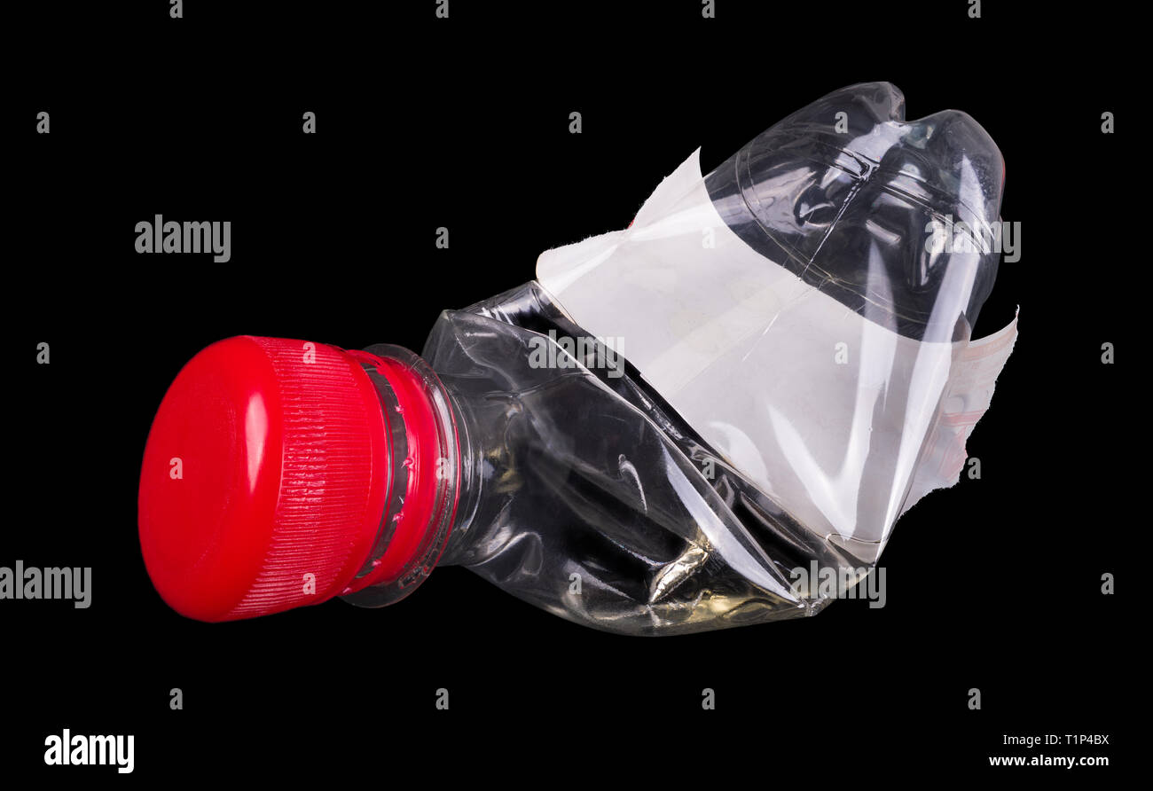 Used plastic bottle. Red cap. White label. Isolated. Black background. One empty transparent PET beverage wrapping. Waste sorting, recycling, disposal. Stock Photo