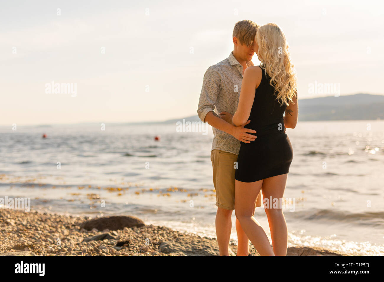 Beautiful young couple in romantic embrace on beach at summer Stock Photo