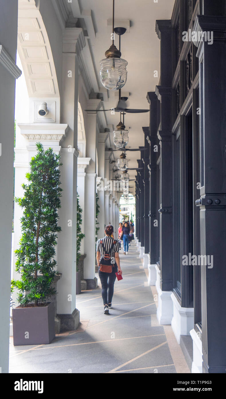 Pedestrians walking along fan cooled portico of Colonial architecture Capitol Kempinski Hotel Singapore Stock Photo
