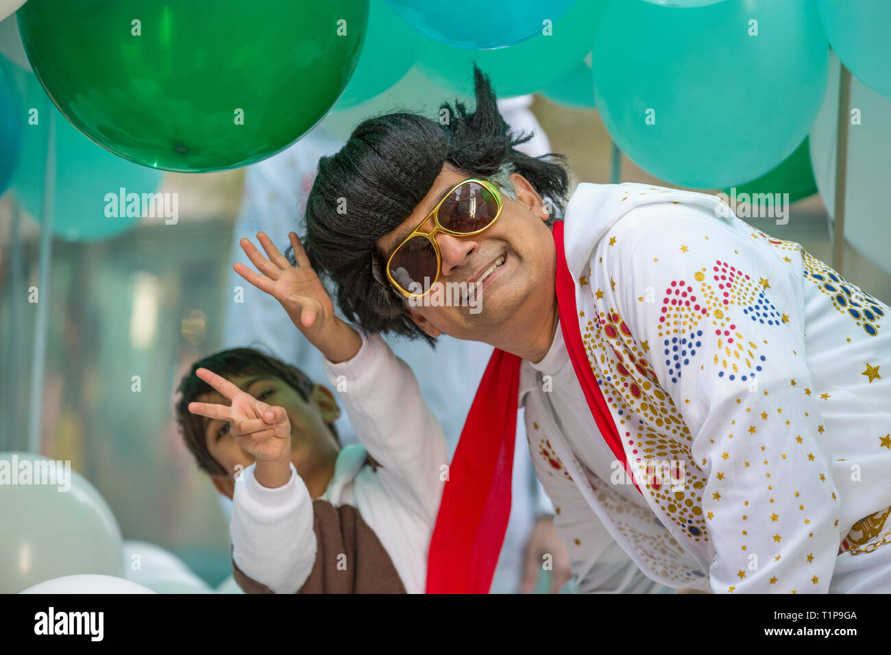 Father dressed in Elvis costume and son giving 'peace' sign participating in annual Chinese New Year Parade in San Francisco, California, USA Stock Photo