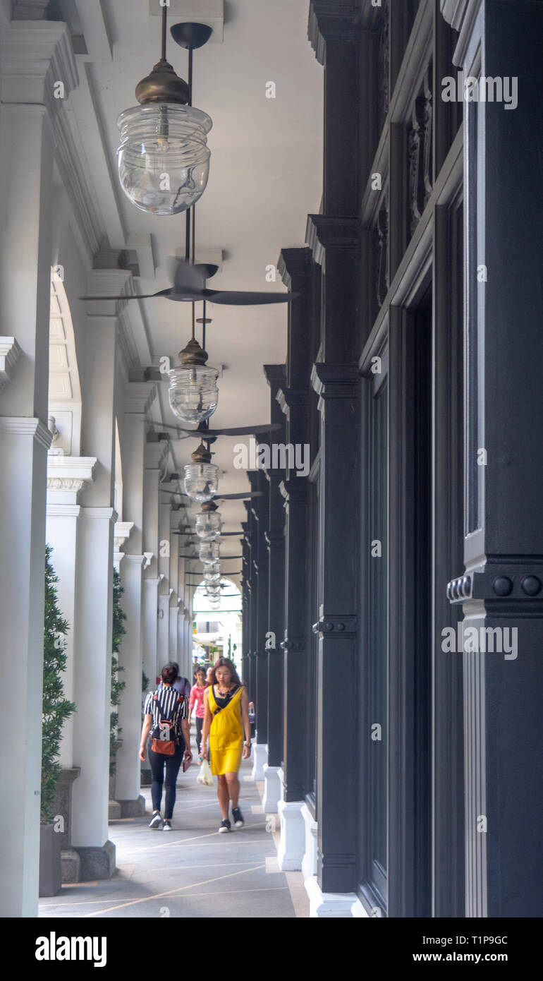 Pedestrians walking along fan cooled portico of Colonial architecture Capitol Kempinski Hotel Singapore Stock Photo