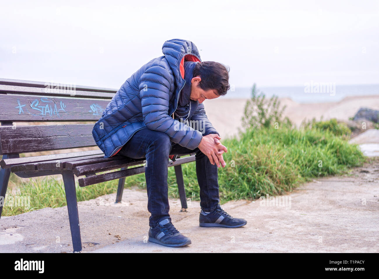 Man sittingo on bench outdoors with head down on the beach Stock Photo -  Alamy