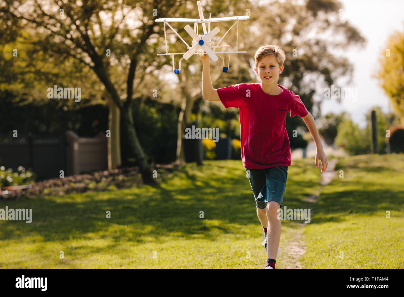 Happy boy playing with a toy plane in the park. Excited boy running ...