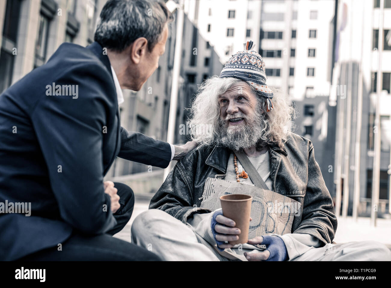 Smiling happy long-haired homeless man taking money from kind businessman  Stock Photo - Alamy