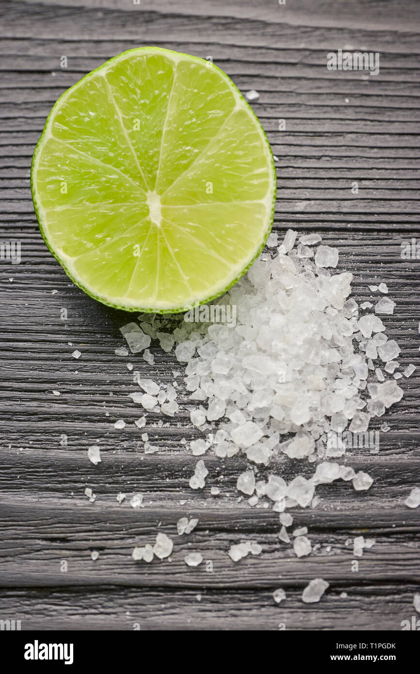 Fresh sliced lime and salt on a wooden table closeup. half lime with salt  Stock Photo - Alamy