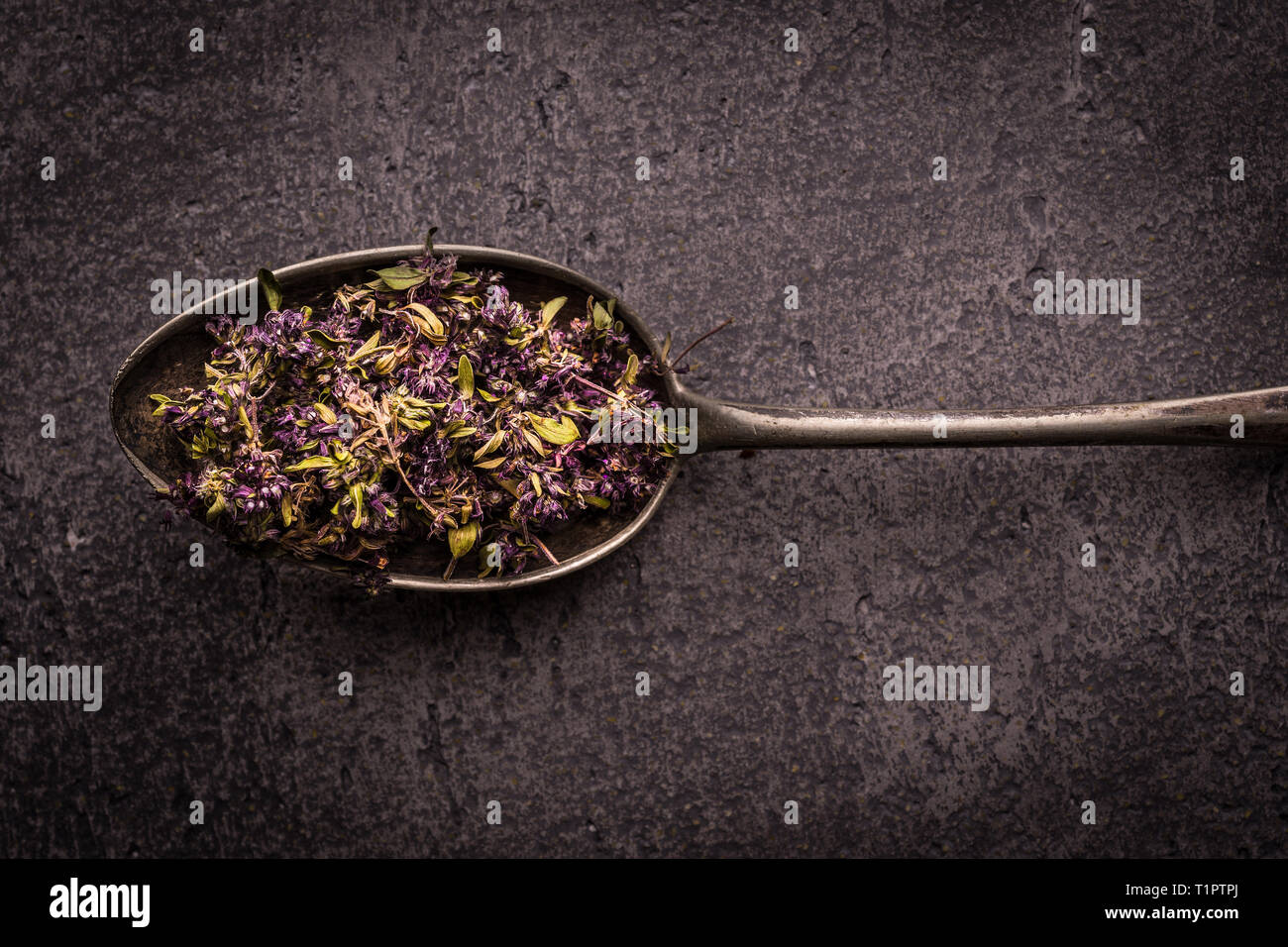Dry Tea Leafs in Rustic Spoon on Dark Stone Background Stock Photo