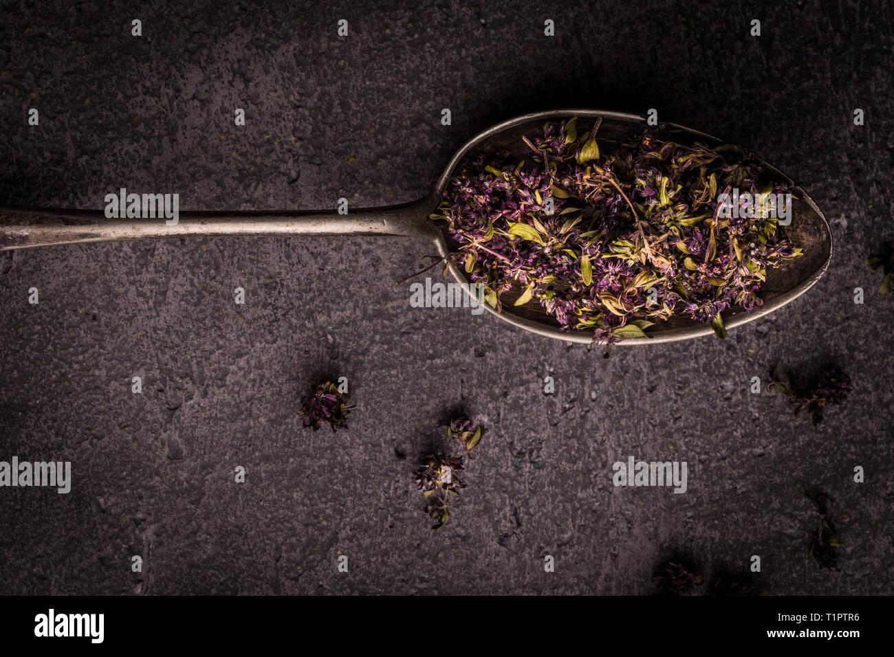 Dry Tea Leafs in Rustic Spoon on Dark Stone Background Stock Photo