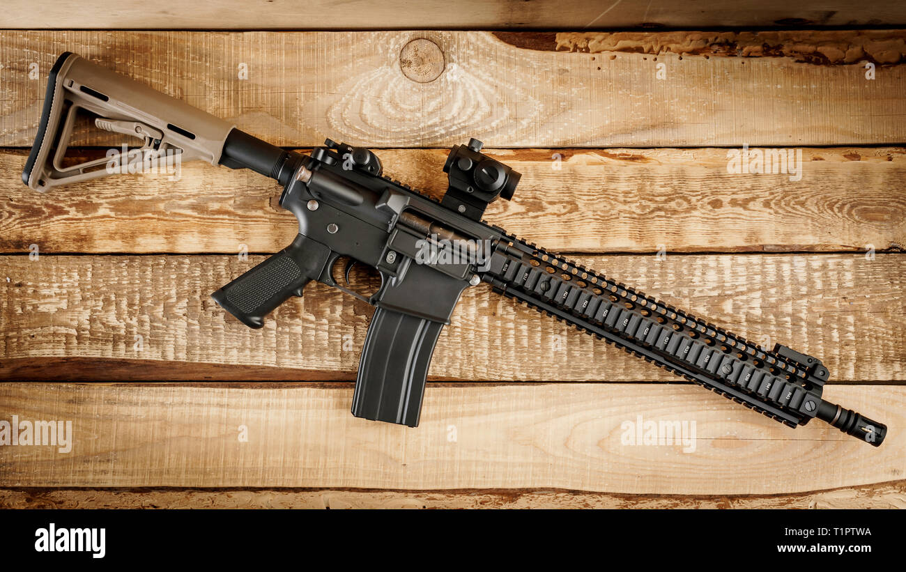 black assault rifle on an old wooden table Stock Photo - Alamy