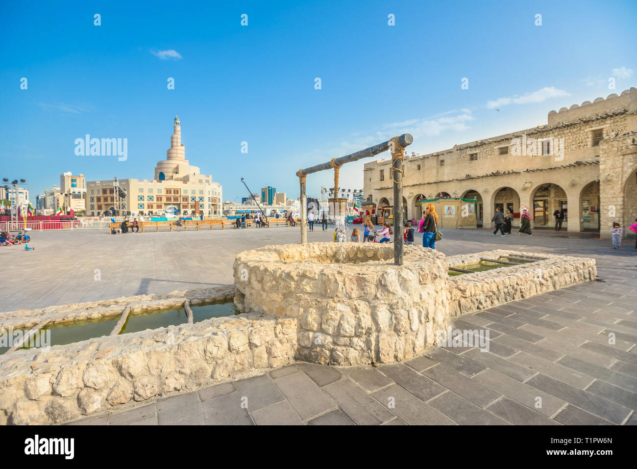 Doha, Qatar - February 20, 2019: old well fountain, famous landmark at Souq Waqif and Fanar Islamic Cultural Center with Spiral Mosque and Minaret on Stock Photo
