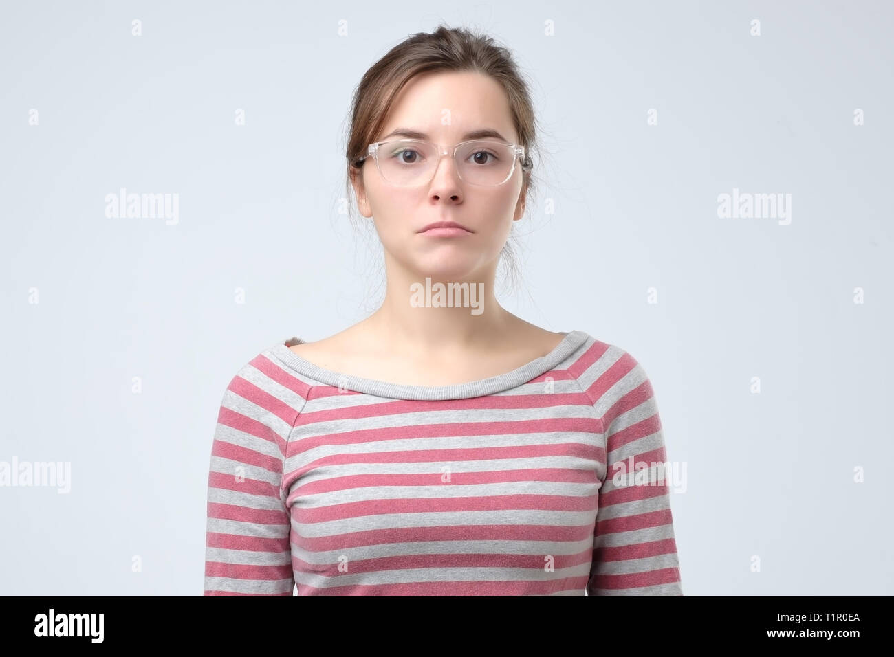 Disappointment concept. Speechless woman in glasses with arms down for disillusion. Studio shoot Stock Photo