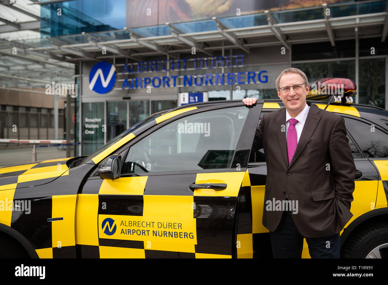 28 March 2019, Bavaria, Nürnberg: Michael Hupe, Managing Director of Albrecht Dürer Airport Nuremberg, stands at the edge of the yearly-Pk at a 'Follow me' vehicle. Photo: Daniel Karmann/dpa Stock Photo