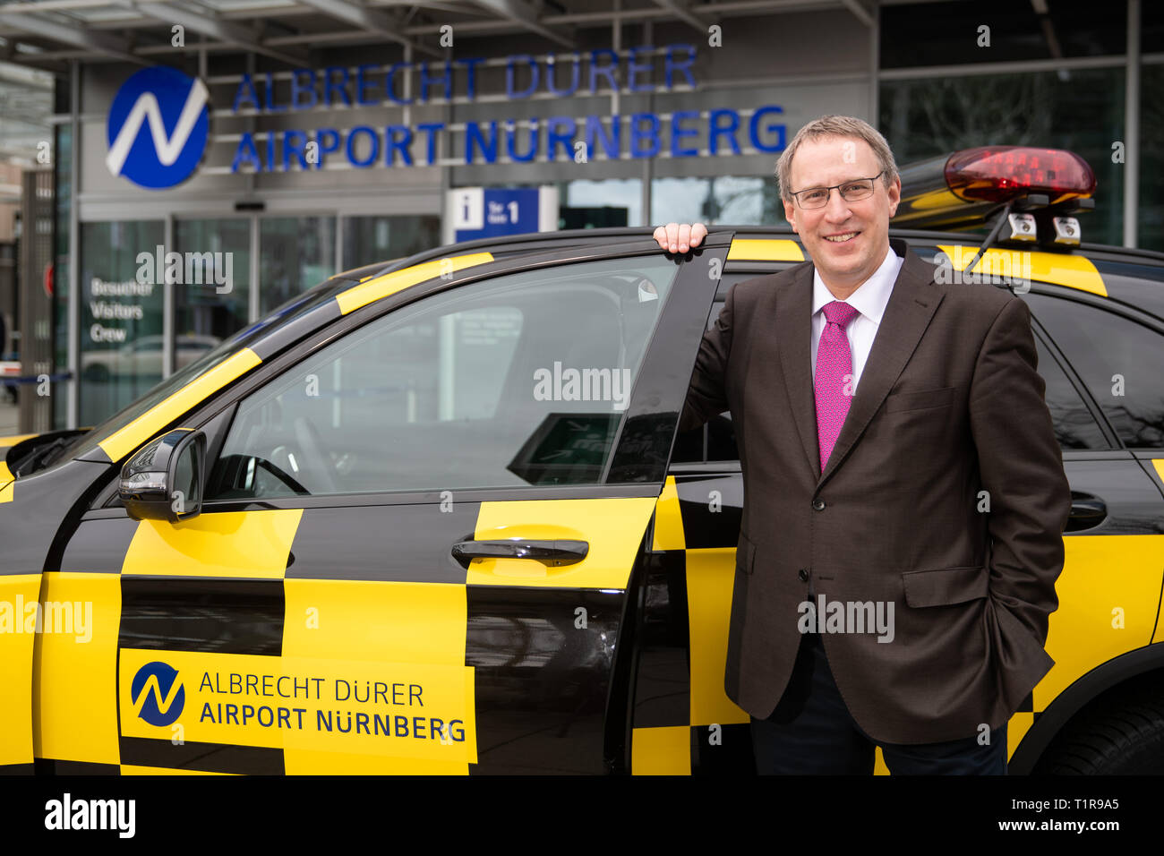 28 March 2019, Bavaria, Nürnberg: Michael Hupe, Managing Director of the Albrecht Dürer Airport Nuremberg, stands at the edge of the annual-Pk at a 'Follow me' vehicle. Photo: Daniel Karmann/dpa Stock Photo