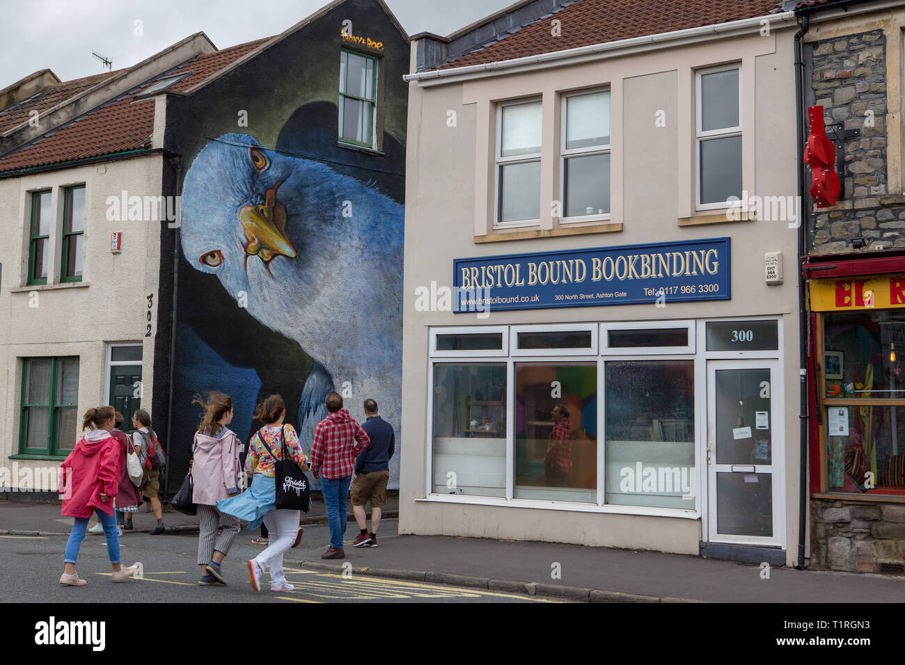 Members of the public crossing North St. to a mural of a giant bird painted on a house wall in the  Upfest streetart festival Bedminster Bristol Stock Photo