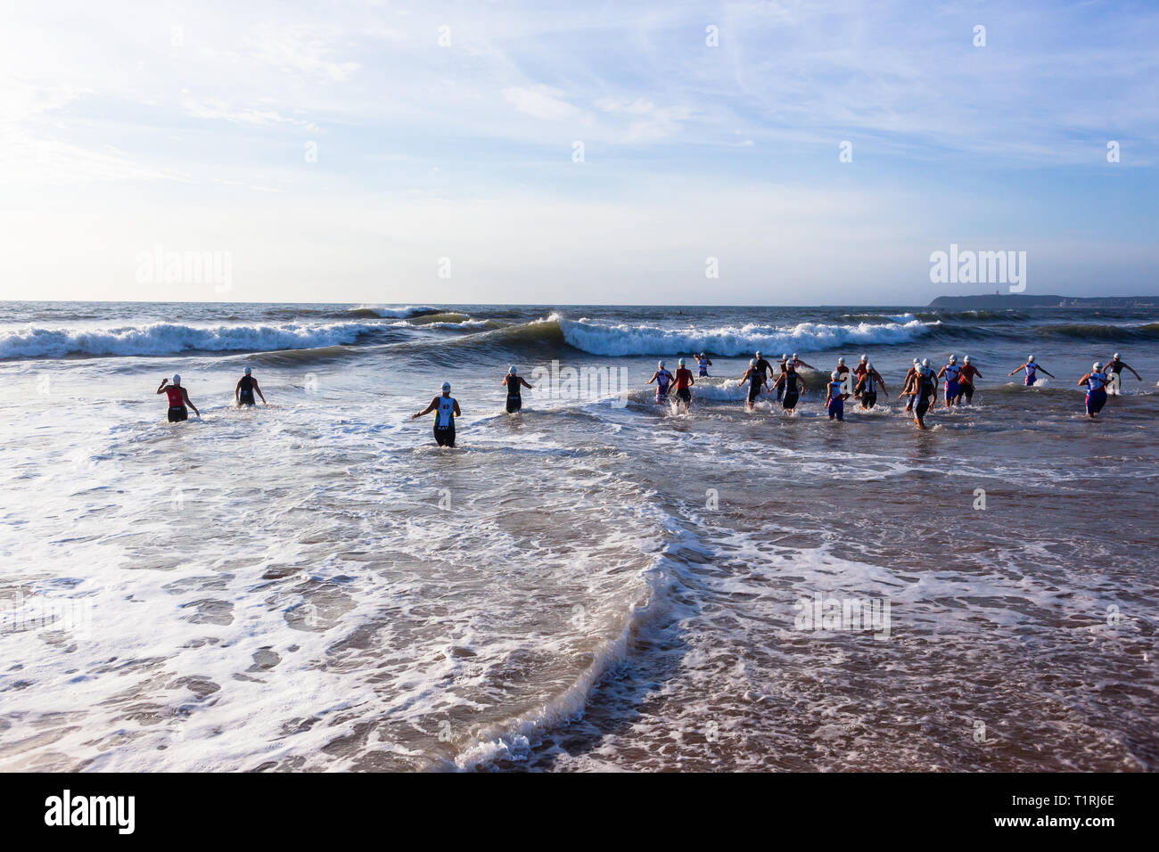 Triathlon National Champs Durban , South-Africa - March 24 , 2019 :     Athletes women running off beach entering ocean wave surf for swimming leg st Stock Photo