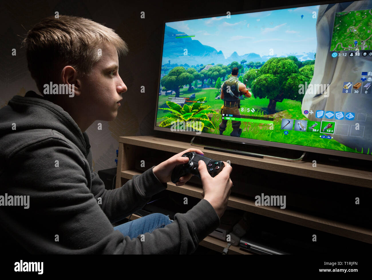 Woman holding a xbox controller and playing popular video game Fortnite on  a television and PC Stock Photo - Alamy