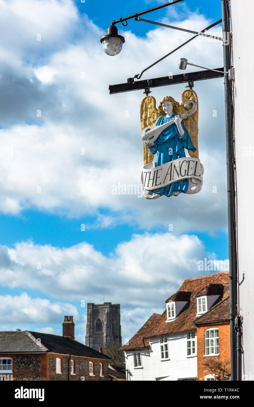 The Angel pub sign in front of the Market Square with St Peter and St Paul's Parish church to the rear. Lavenham village, Suffolk, England, UK. Stock Photo