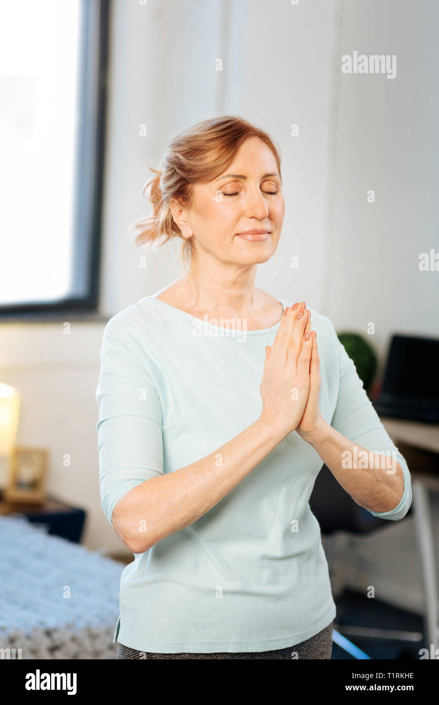Tranquil active mature woman standing with connected hands Stock Photo
