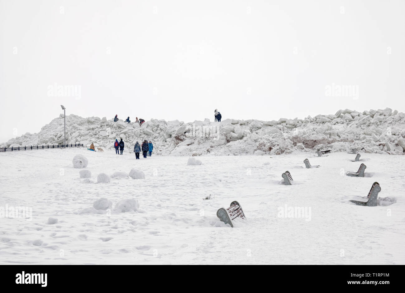 People walk near pressure ridges (ice floes) on The Gulf of Finland on the beach of Zelenogorsk Town (district of St Petersburg) in March. Russia Stock Photo