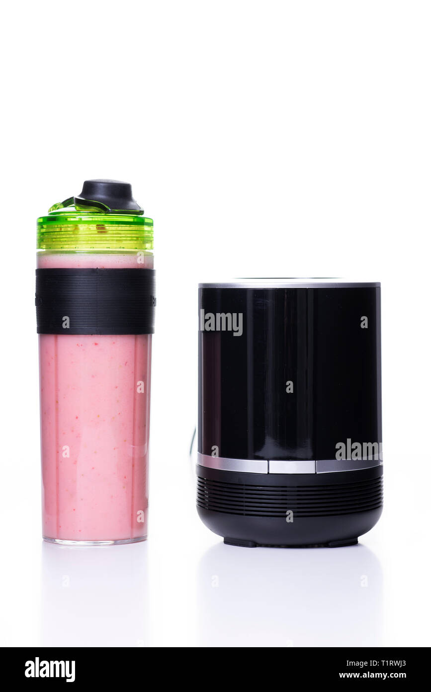 a black blender and a pink smoothie in its transparent jar, with a cap to use as a sports bottle, on a white background Stock Photo