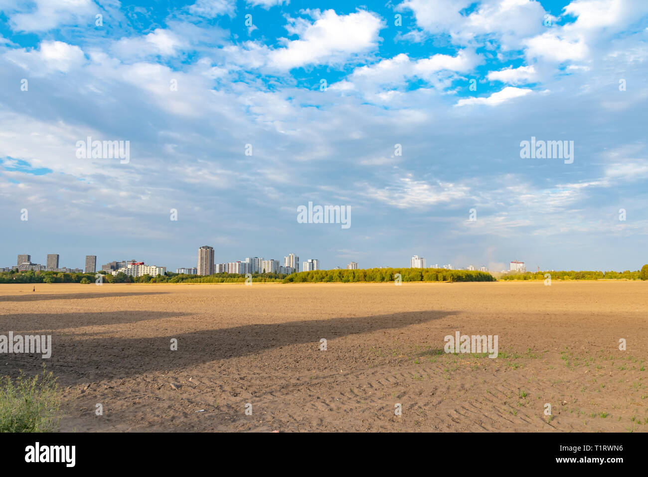 View over a harvested field to the satellite city Gropiusstadt in Berlin-Neukoelln illuminated by the sun. Stock Photo