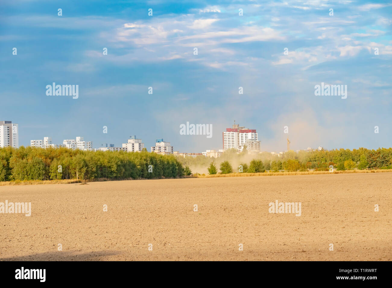 View over a harvested field to the satellite city Gropiusstadt in Berlin-Neukoelln illuminated by the sun. Stock Photo
