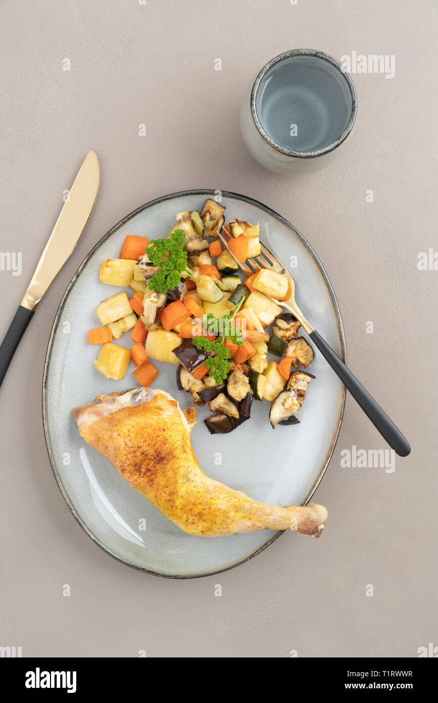 Place setting chicken dinner with oven roasted chicken leg and roasted
