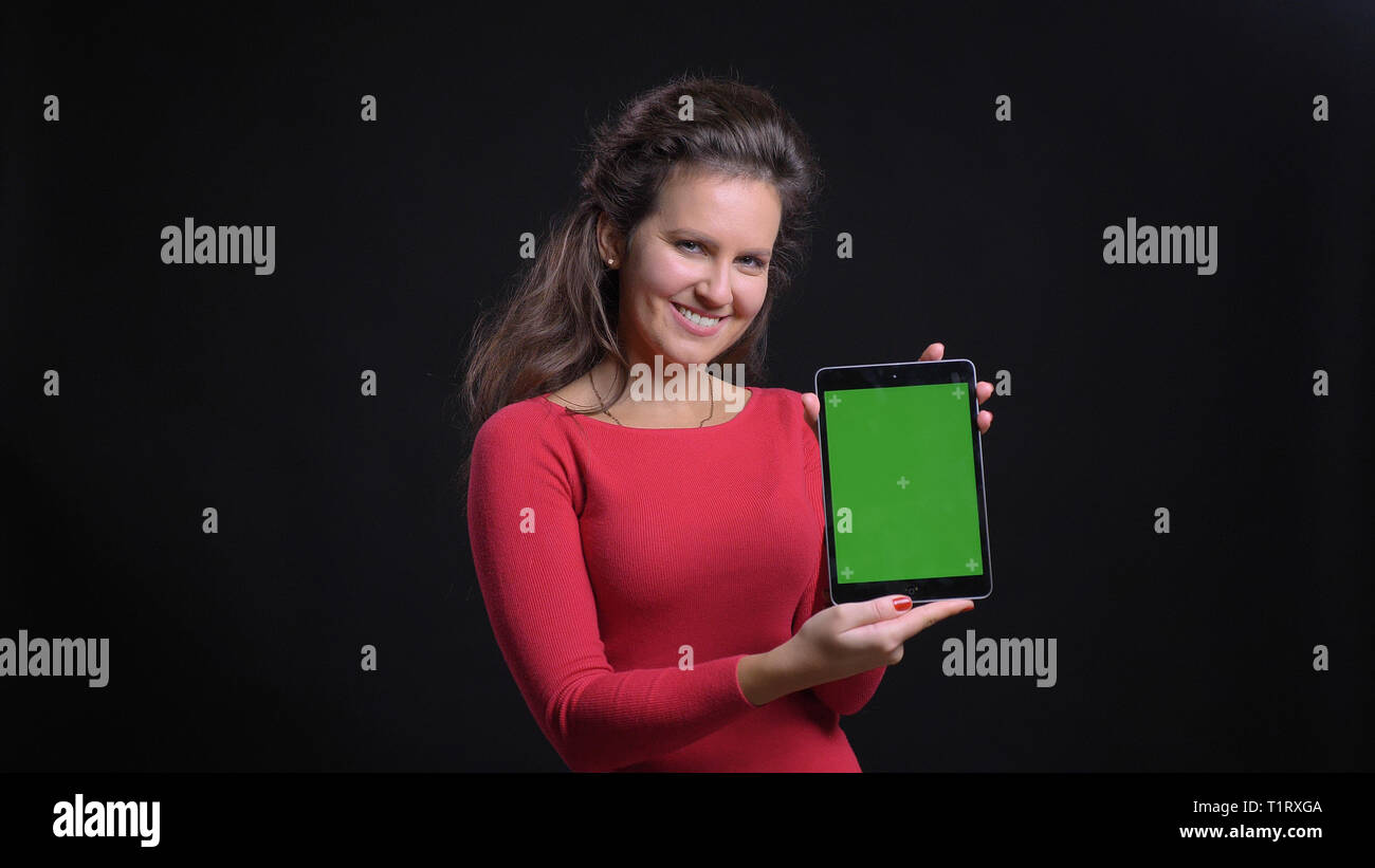 Closeup portrait of attractive middle-aged caucasian using the tablet and showing green chroma screen to camera cheerfully smiling Stock Photo