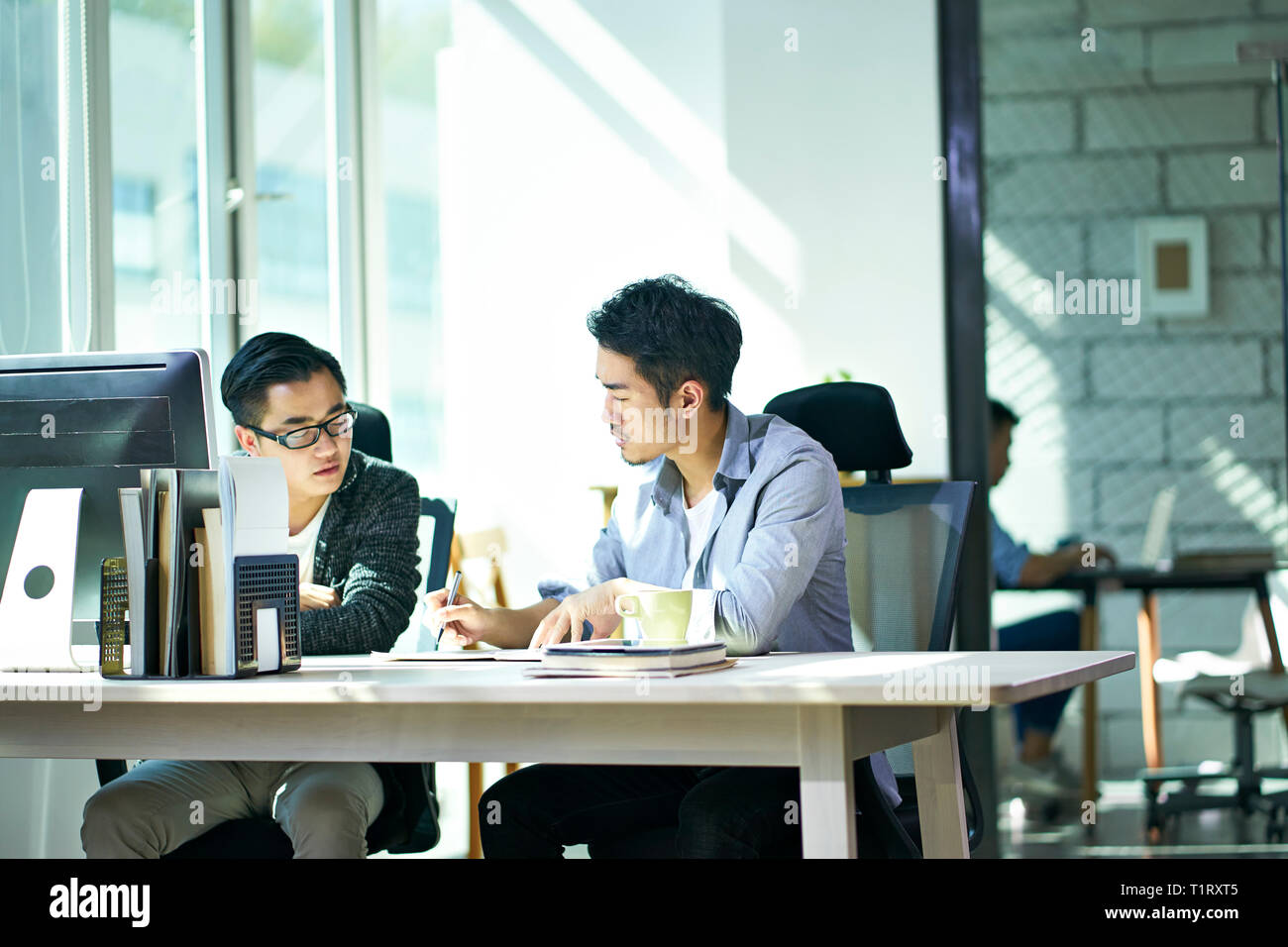 two young asian business people working together in office discussing business. Stock Photo