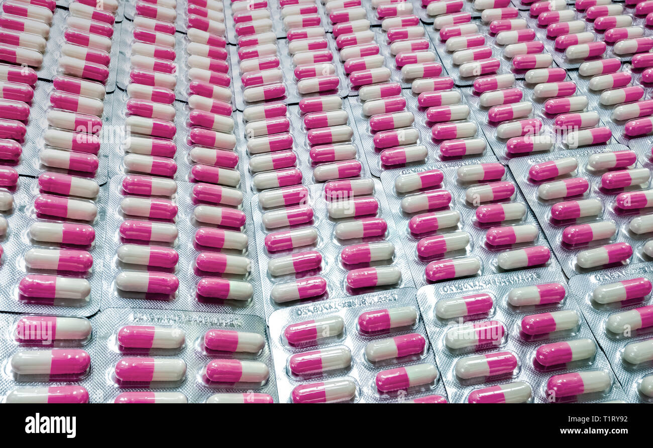 Closeup pink-white antibiotic capsule pills in blister pack. Antibiotic drug resistance. Pharmaceutical industry. Global healthcare. Pharmacy backgrou Stock Photo