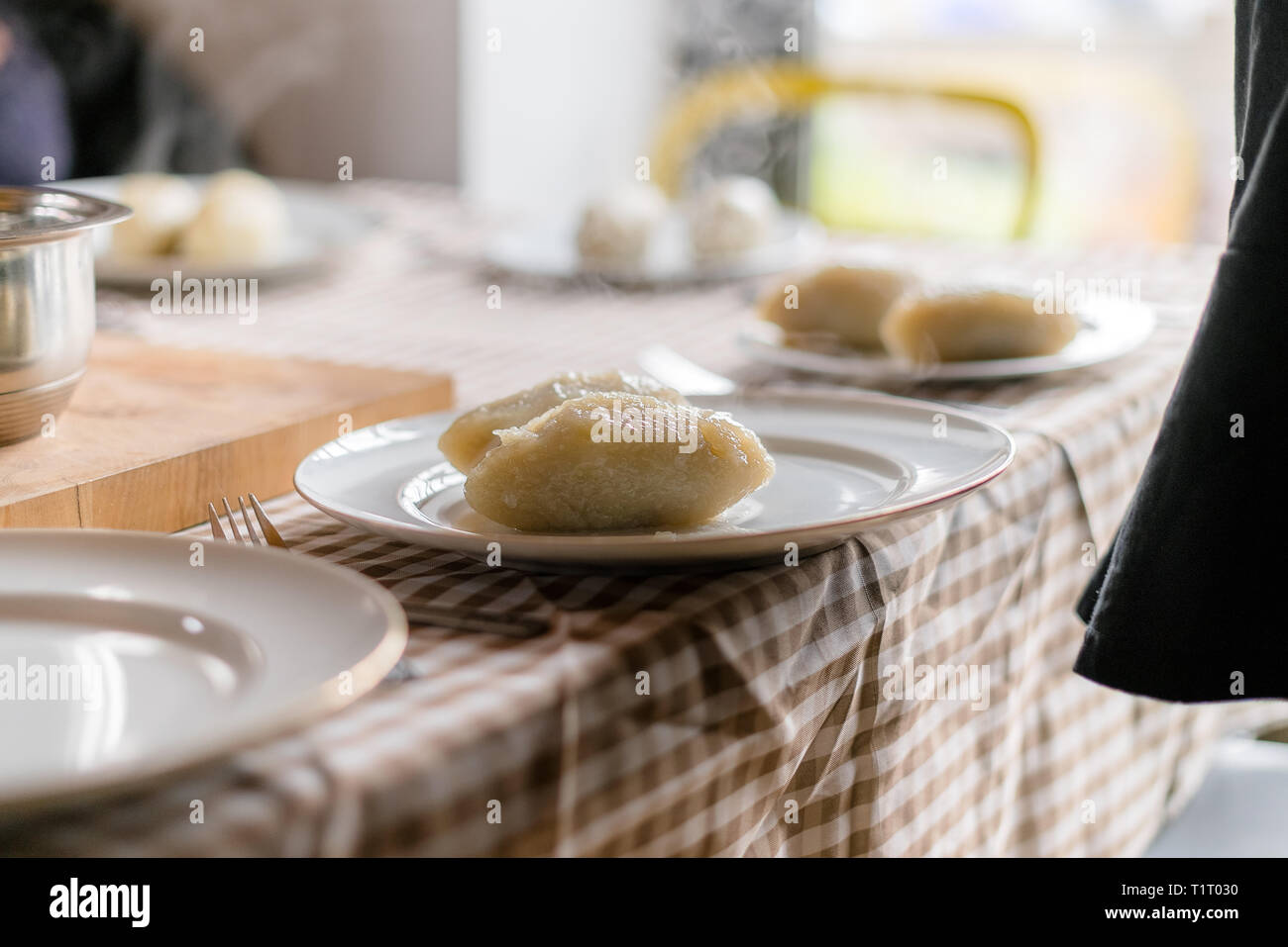 Making of Cepelinai - Zeppelins is national Lithuanian dish. Serving hot zeppelins on a plate at home Stock Photo