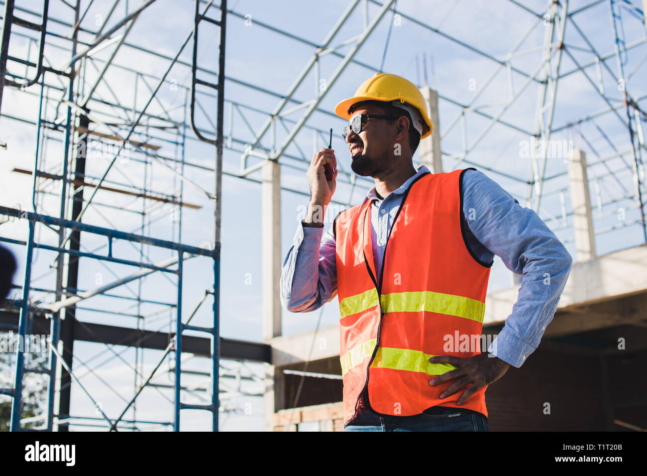 engineer holding radio and ordering at construction working site Stock