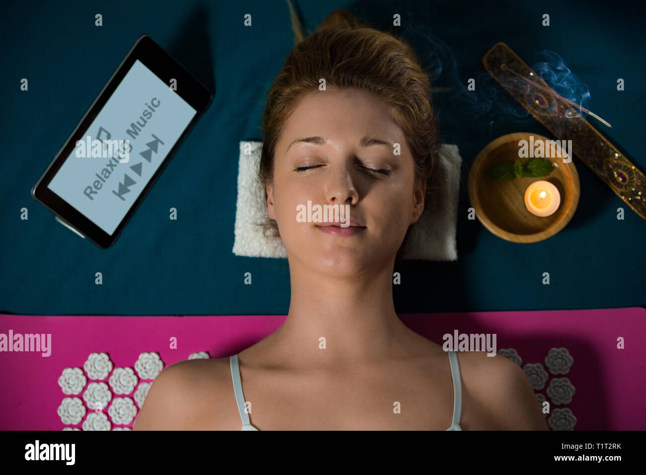 Woman with closed eyes Relaxing at home, lying on acupuncture mat