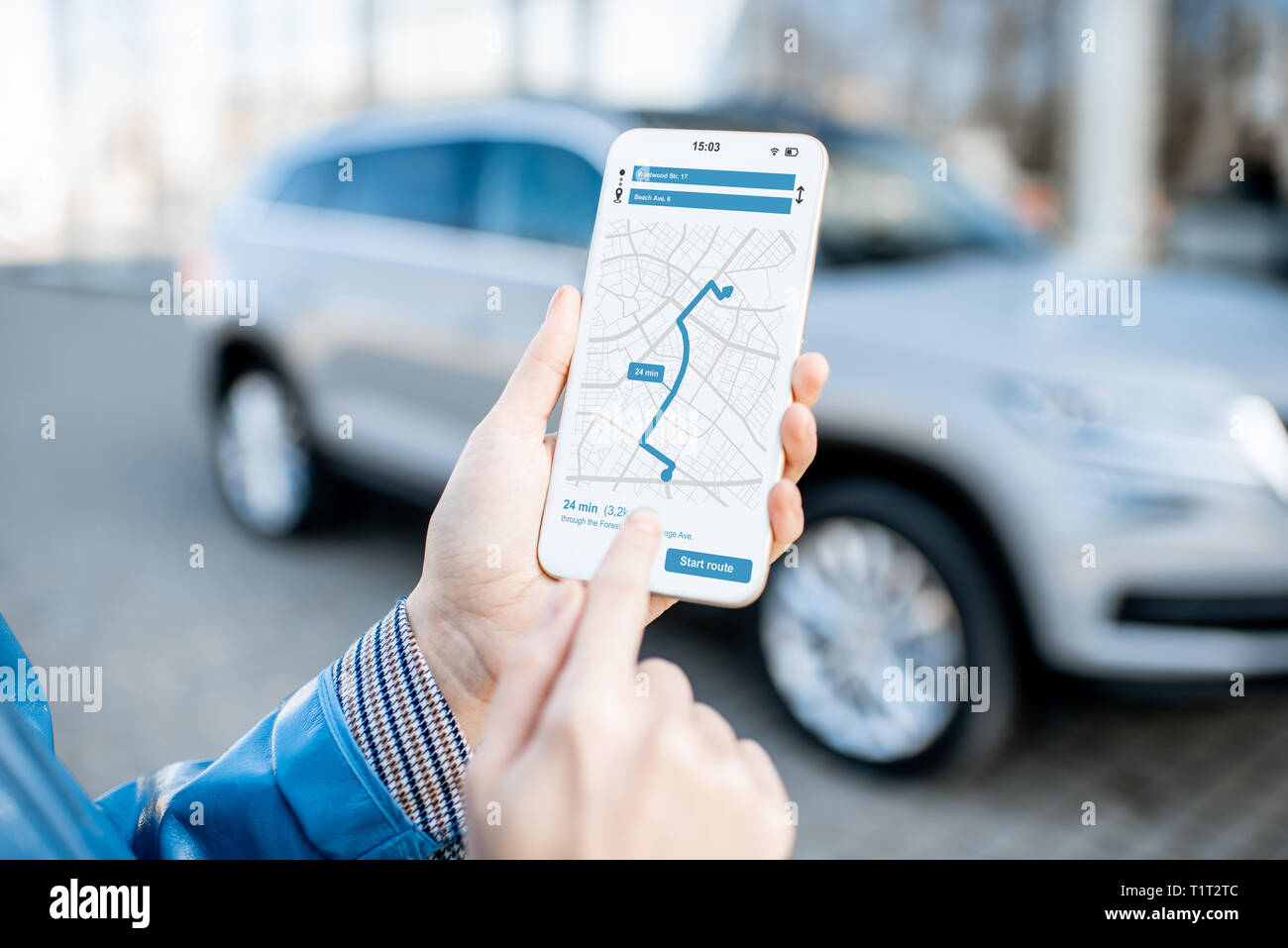 Woman using smart phone with navigation app, close-up view with modern car on the background Stock Photo