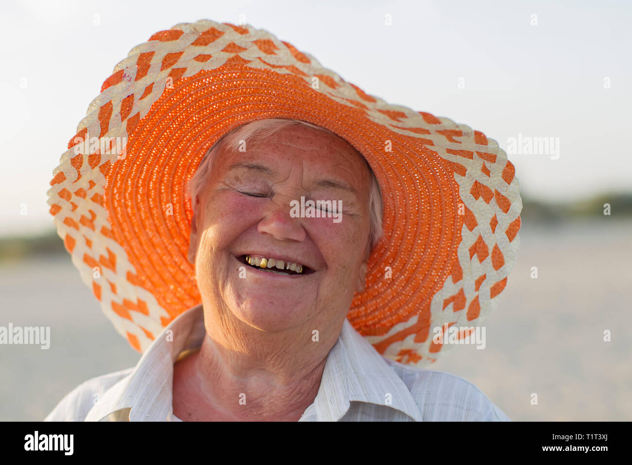 The face of an old woman. Grandmother on vacation. Cheerful old lady in a hat laughing happily. Smile with artificial teeth Stock Photo