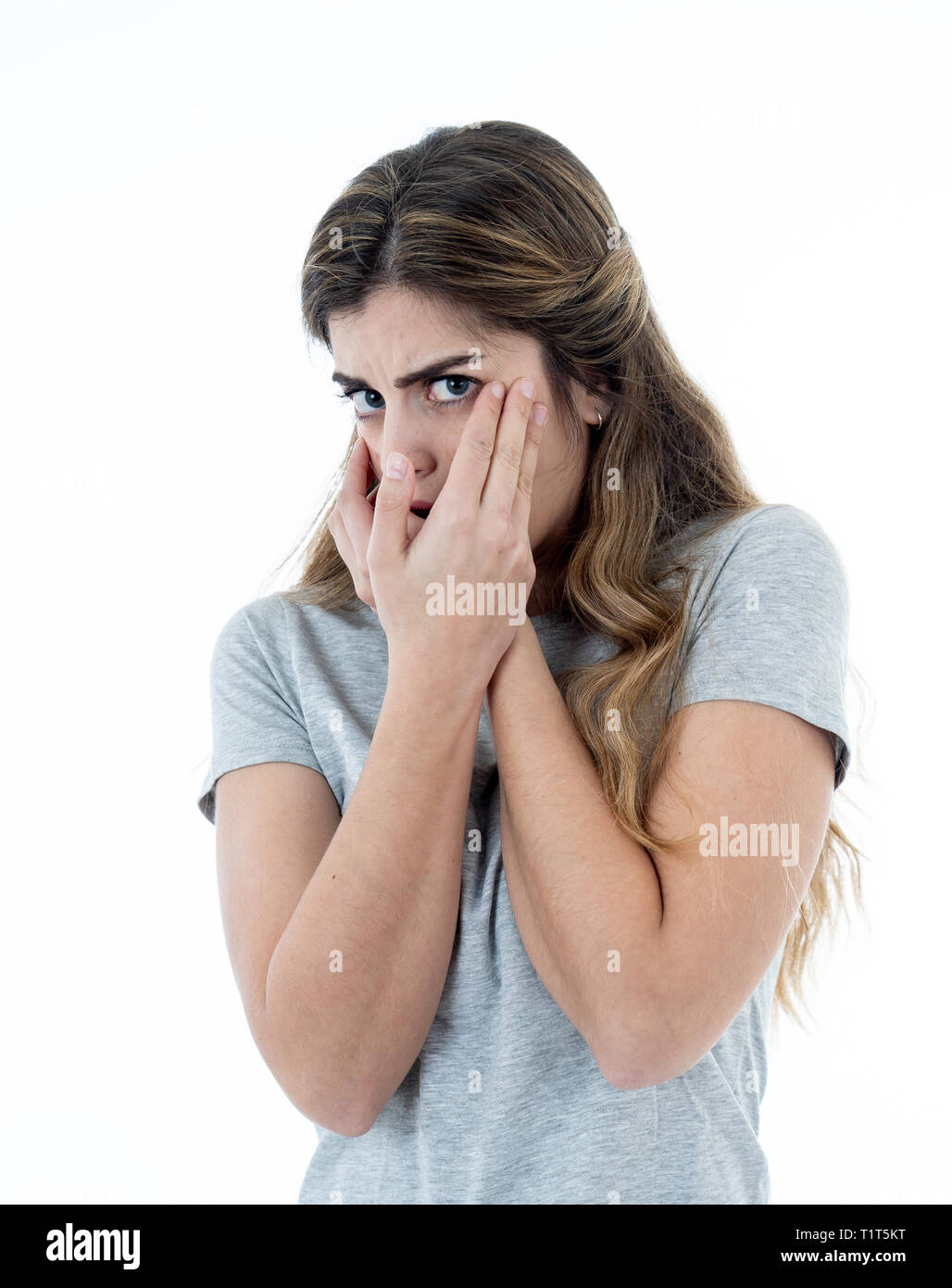 Close up portrait of young woman feeling afraid and shocked hiding her face from something scary. Looking with fear in her eyes. People and Human expr Stock Photo