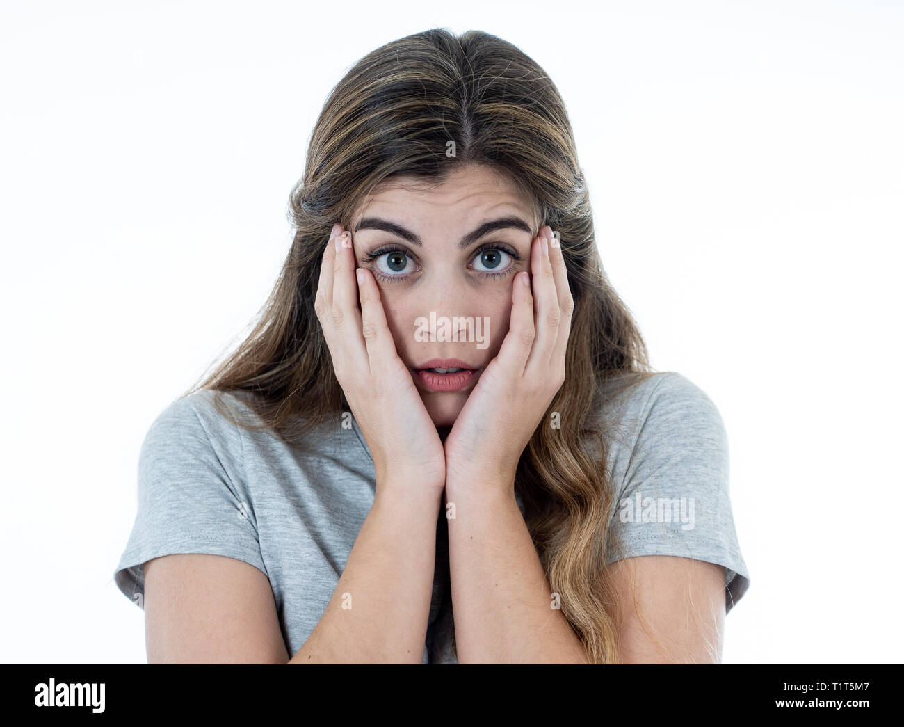 Close up portrait of young woman feeling afraid and shocked hiding her face from something scary. Looking with fear in her eyes. People and Human expr Stock Photo
