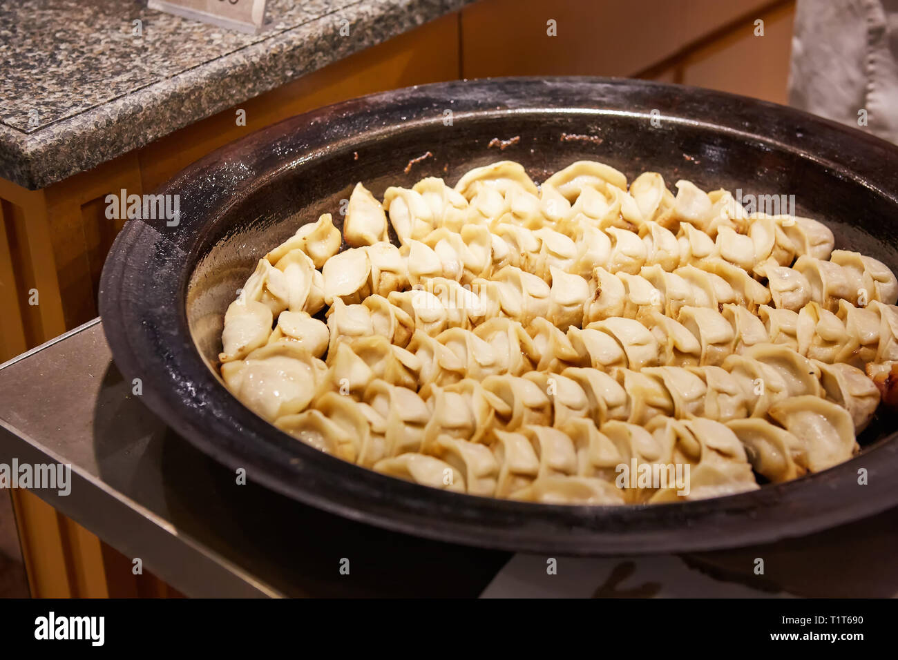 big frying pan with sheng jian bao-traditional chinese pan fried dumplings with minced pork shrimp and vegetables in Shanghai China, Cantonese food Stock Photo