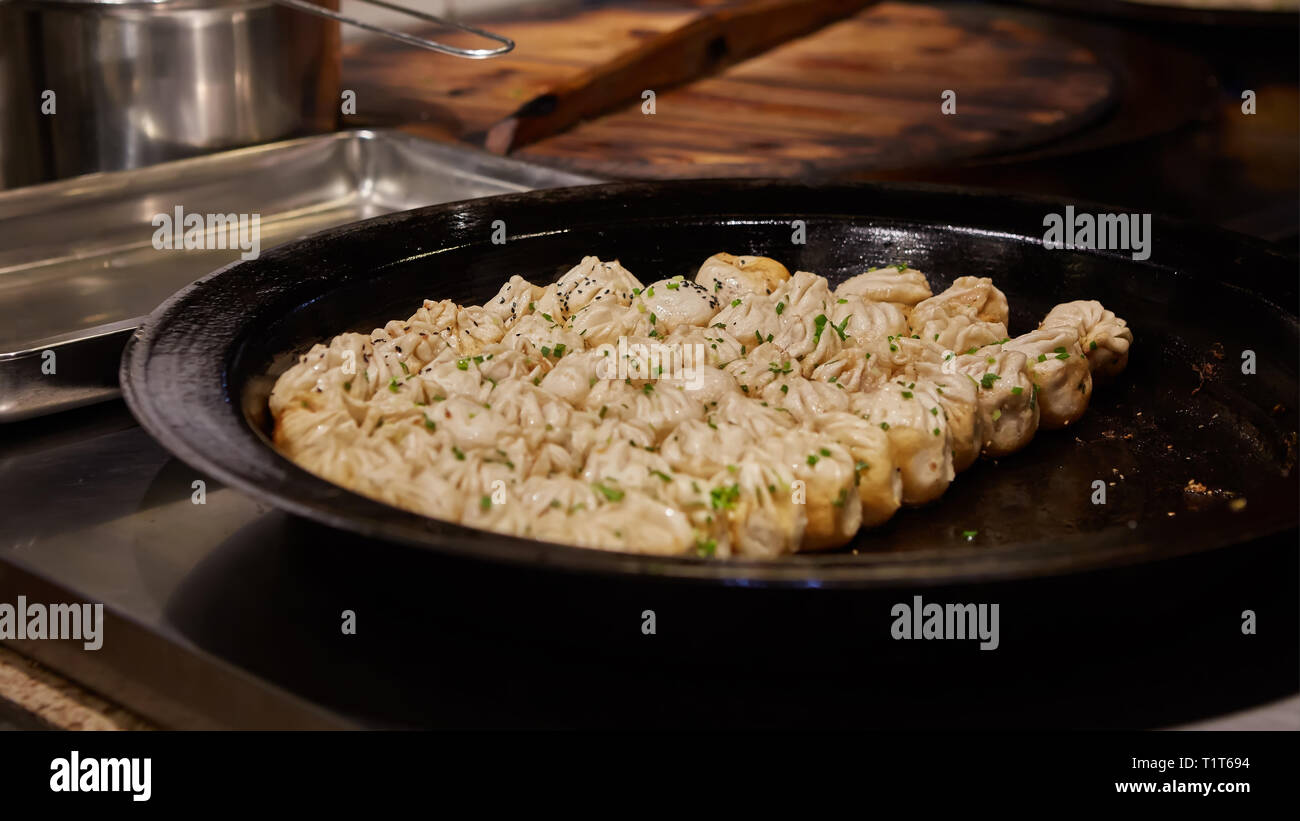 big frying pan with sheng jian bao-traditional chinese pan fried dumplings with minced pork shrimp and vegetables in Shanghai China, Cantonese food Stock Photo