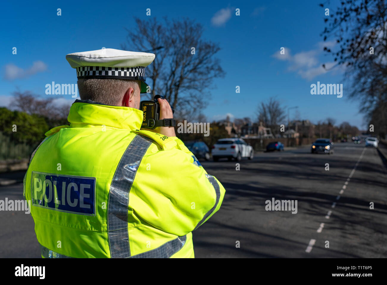 Traffic police officer holding a radar speed camera at an urban speed control checkpoint in Edinburgh, Scotland UK Stock Photo