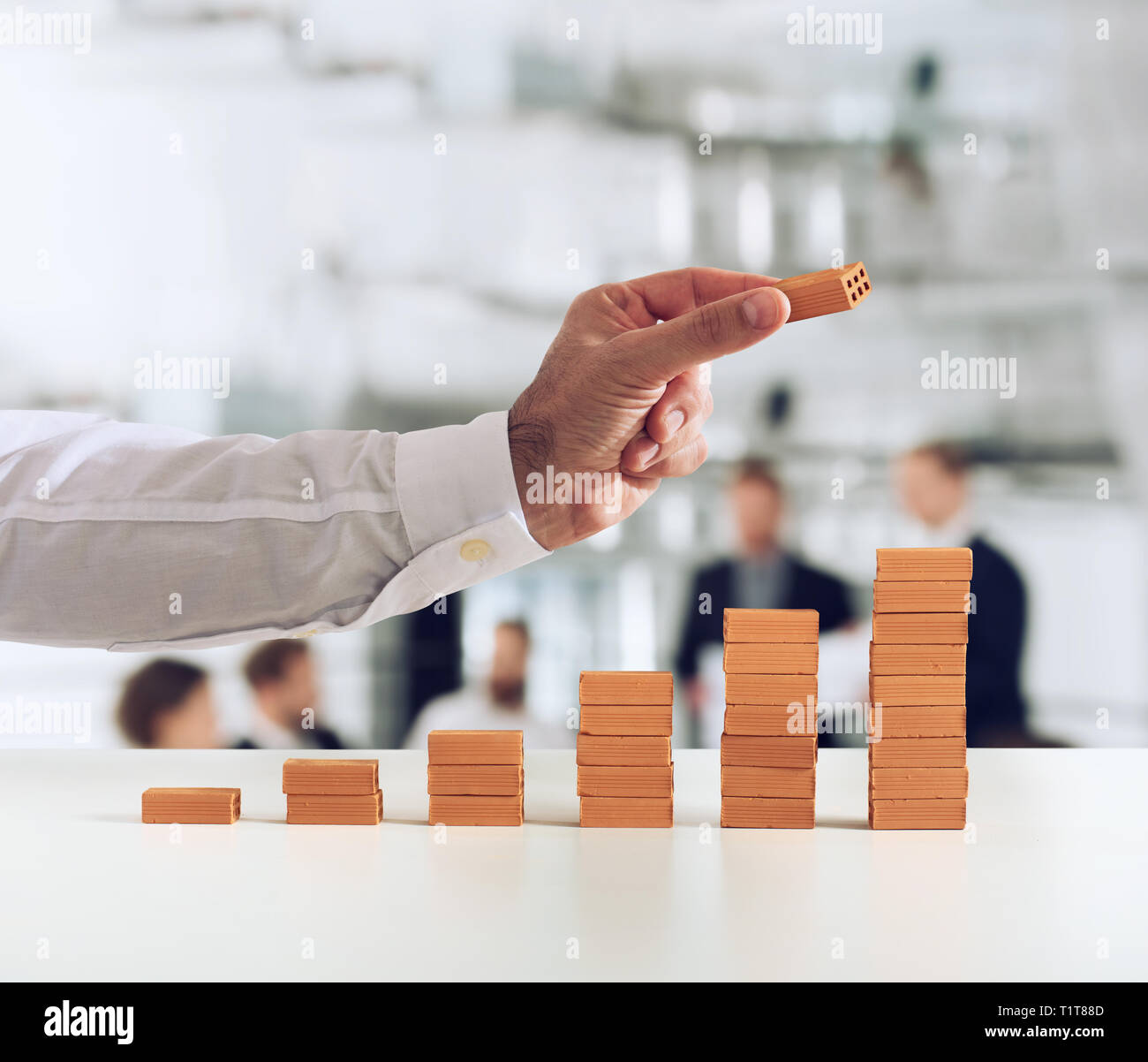 Businessman puts a brick on a bricks pile. Concept of growing statistics and success Stock Photo