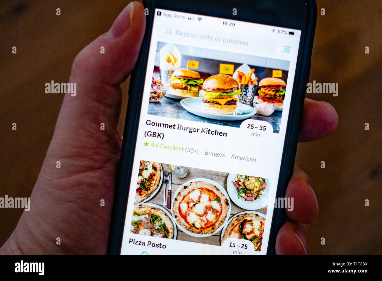 Using a mobile phone to use Deliveroo food delivery app Stock Photo