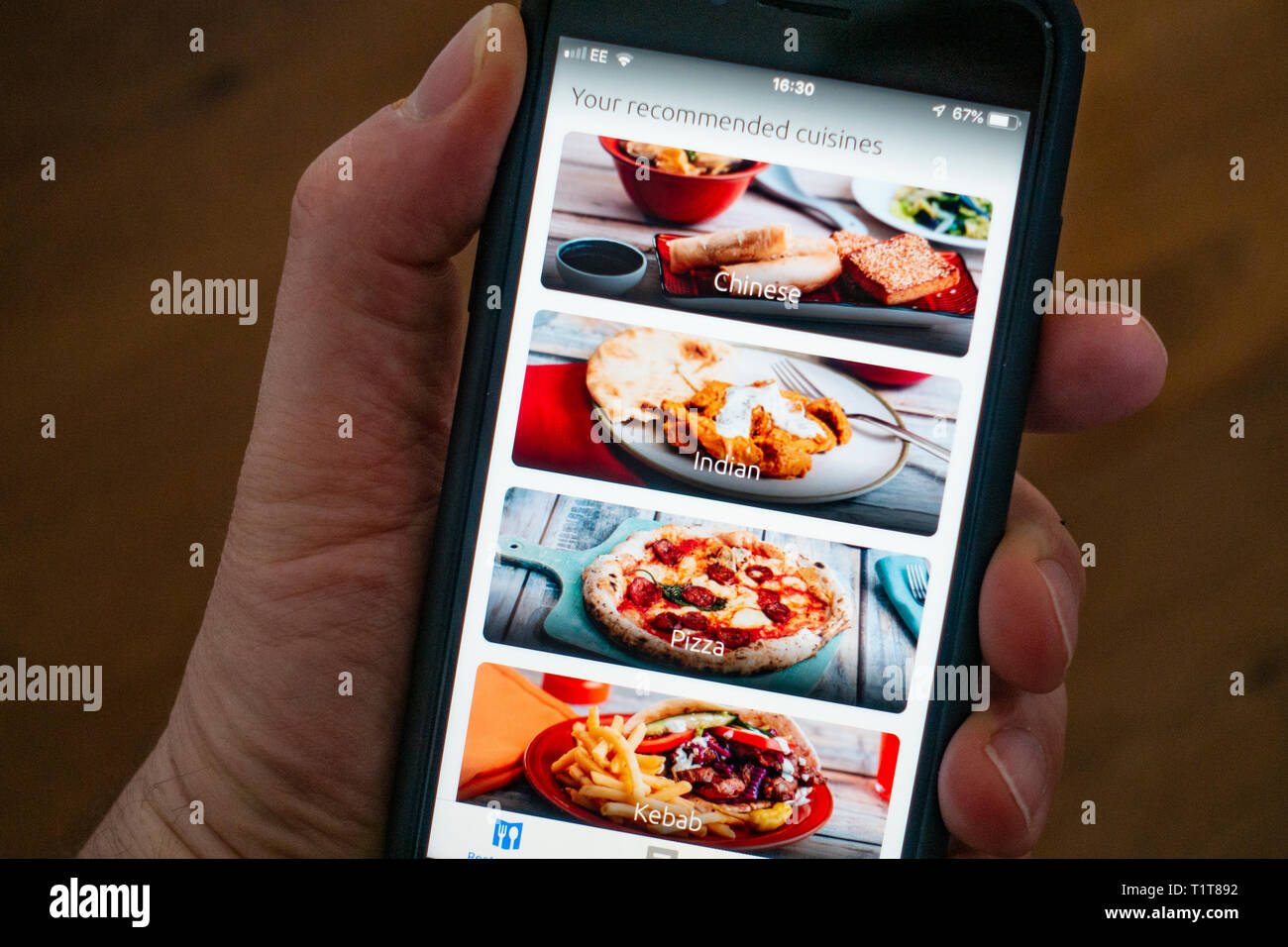Using a mobile phone to use Just Eat food delivery app Stock Photo