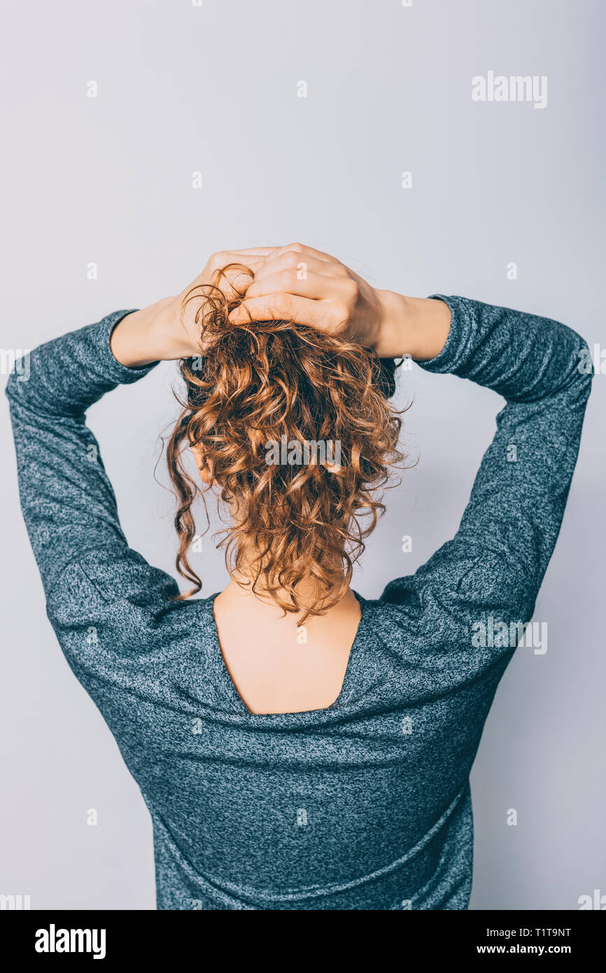 Back view of young woman with shiny curly hair making her ponytail  hairstyle on white background Stock Photo - Alamy