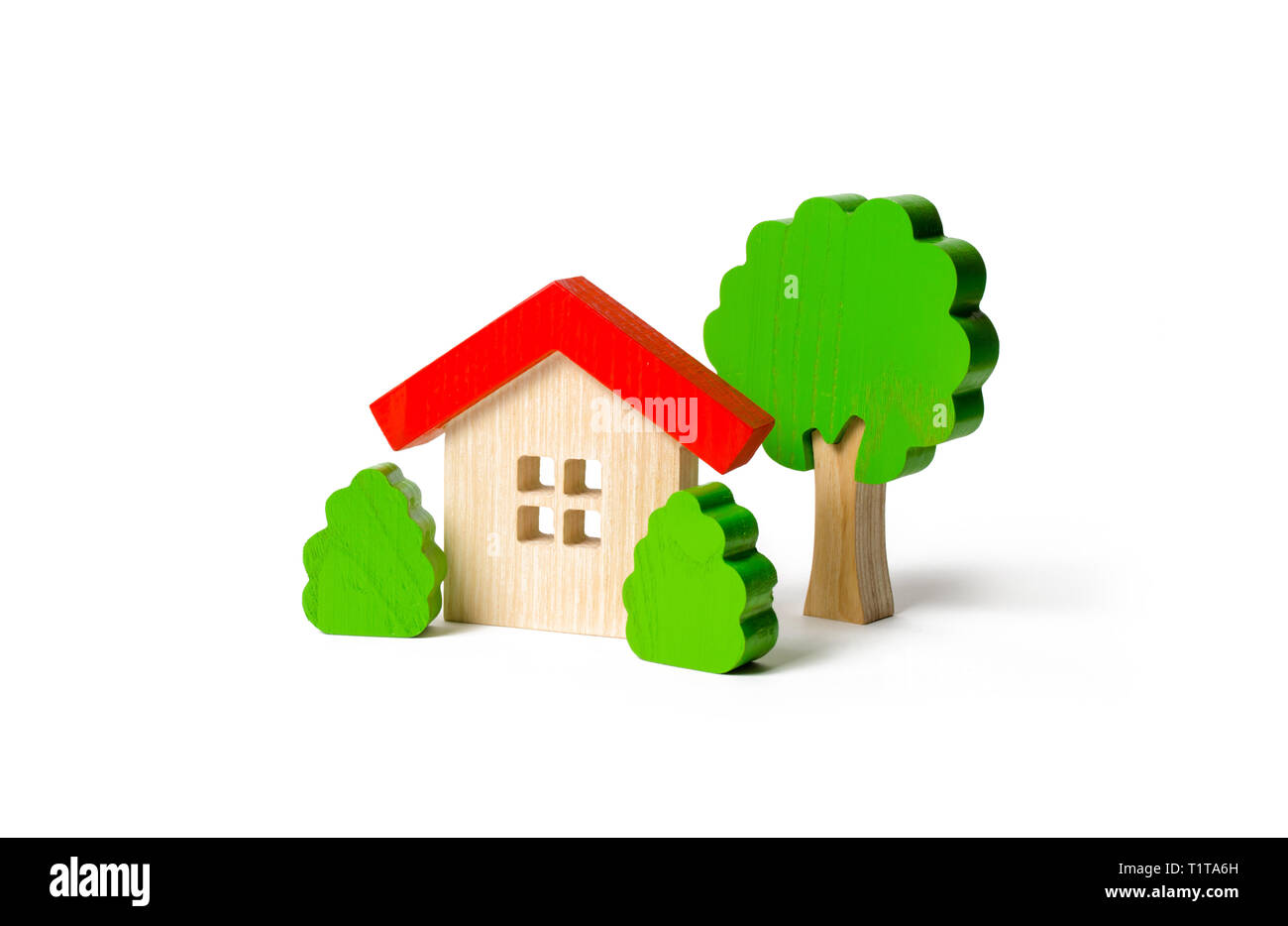 Wooden hut and tree figurines with bushes on an isolated background. The concept of a love nest. Country estate. Acquisition of affordable housing in  Stock Photo
