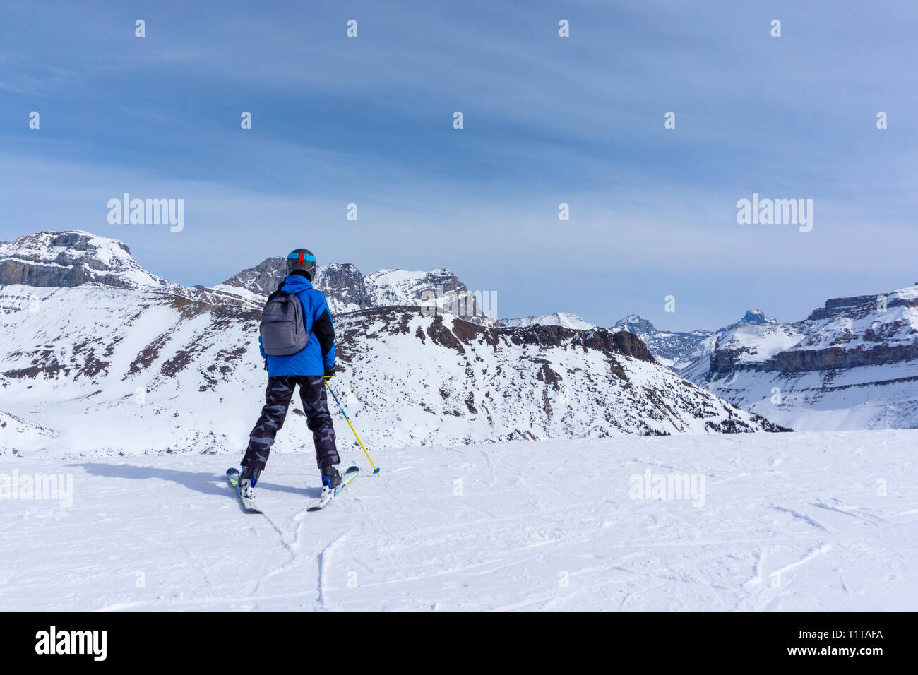 Young skier standing at the edge of a mountain range in Lake Louise looking at the Canadian Rockies of Alberta, Canada. Stock Photo