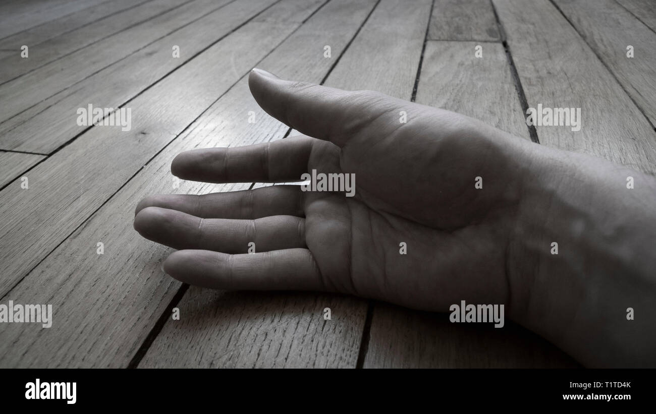 Male hand resting against wooden floor Stock Photo