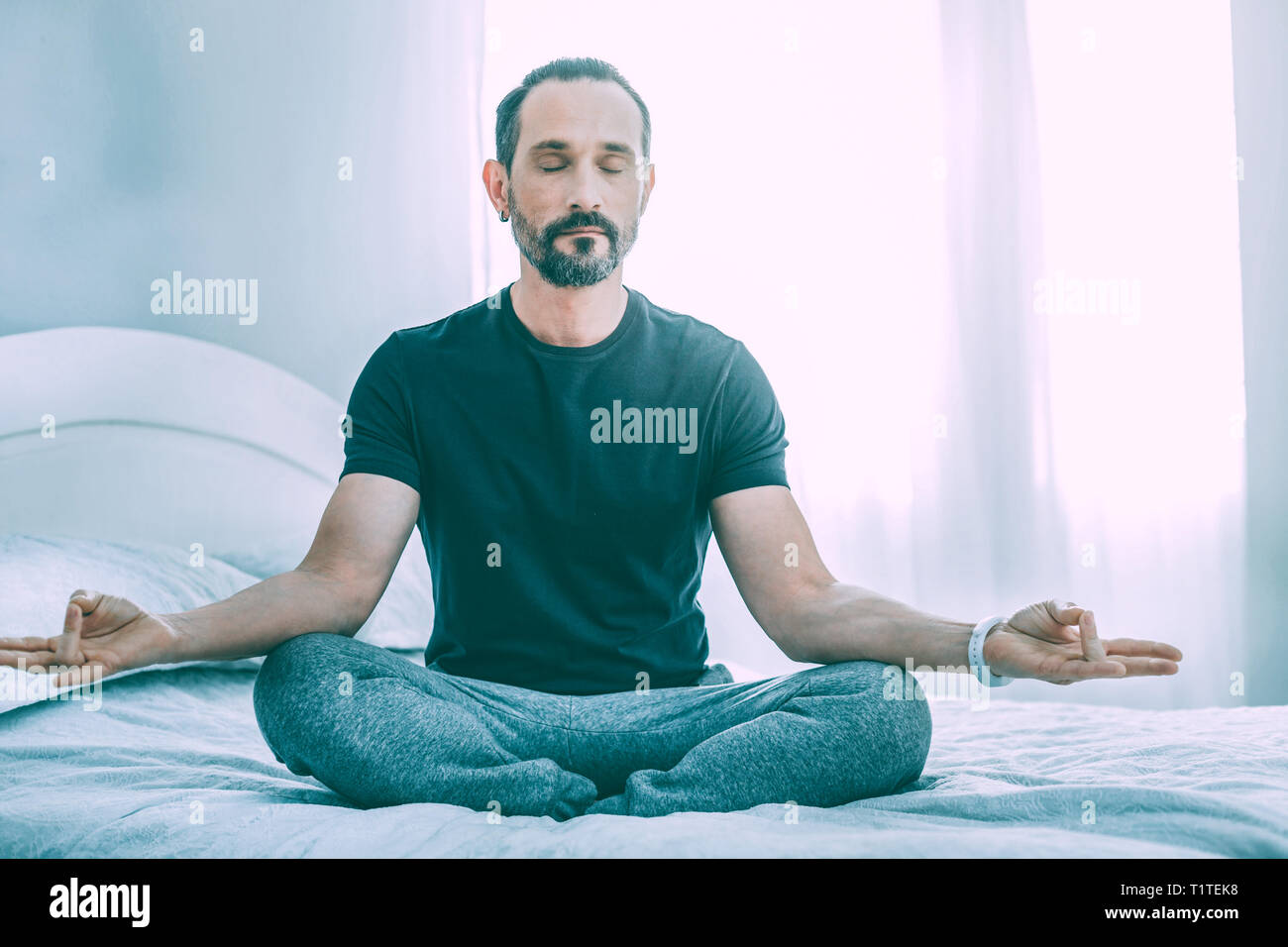 Relaxed concentrated man meditating in a room Stock Photo
