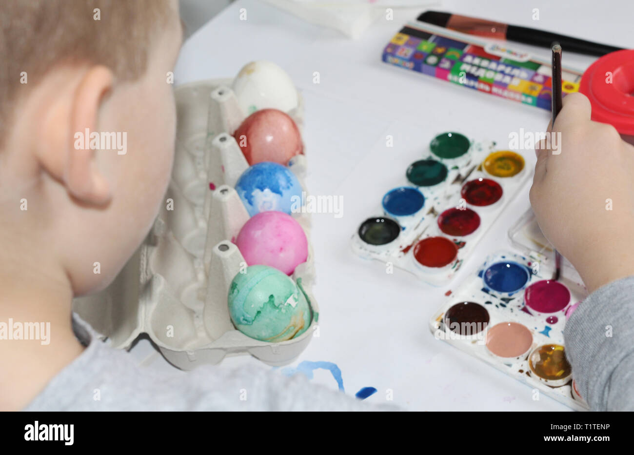 A child paints eggs with a brush. Paint the eggs for Easter. Marble colored eggs. Pastel shades. Easter eggs. Stock Photo
