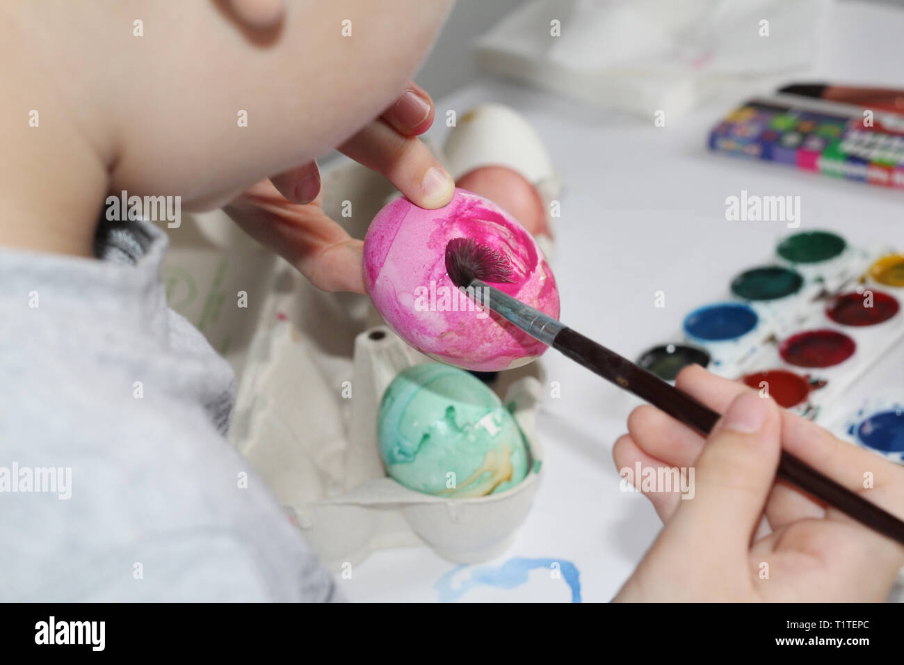 A child paints eggs with a brush. Paint the eggs for Easter. Marble