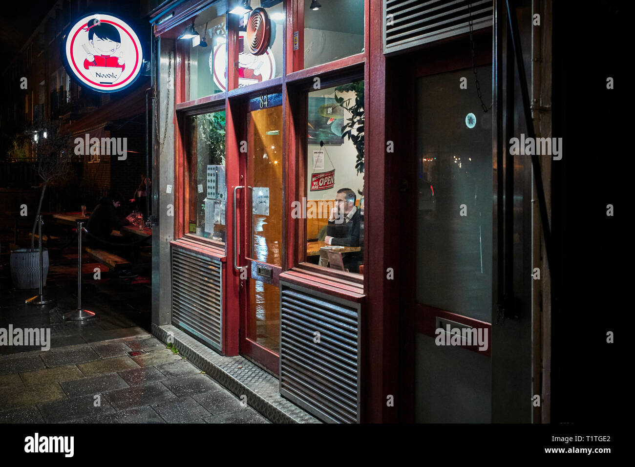 Man sitting in a noodle bar on The Cut, near Waterloo station, London Stock Photo